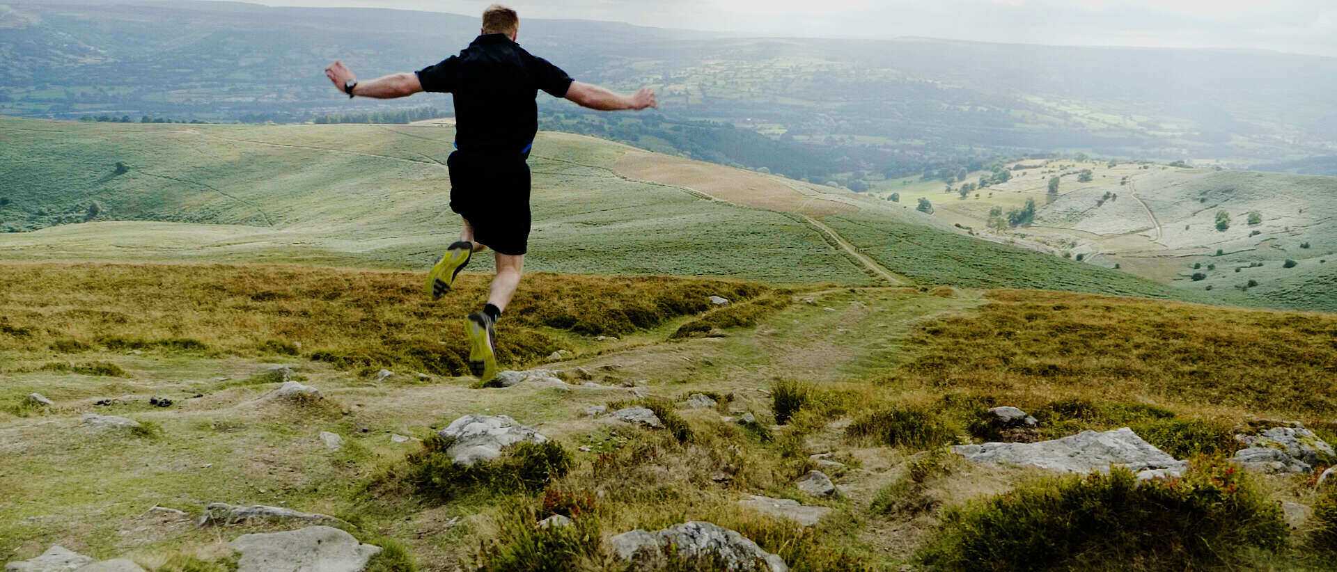 A man jumps on the top of the Sugarloaf Mountain on a cloudy and foggy day.